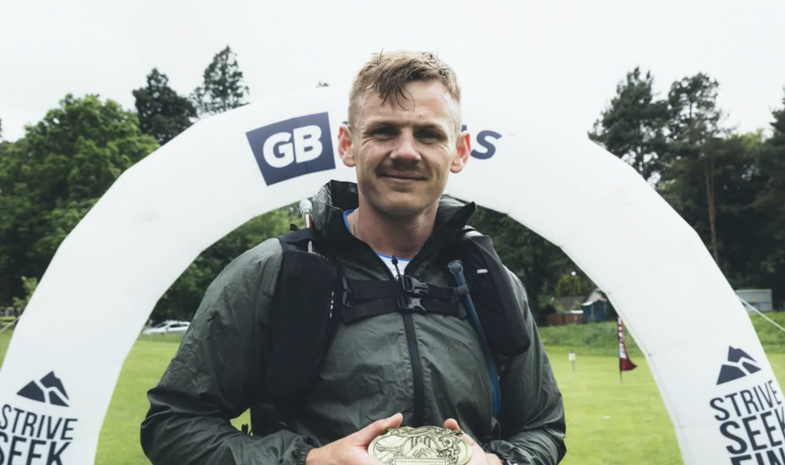 Jimmy holding a medal beneath a GB Ultras arch