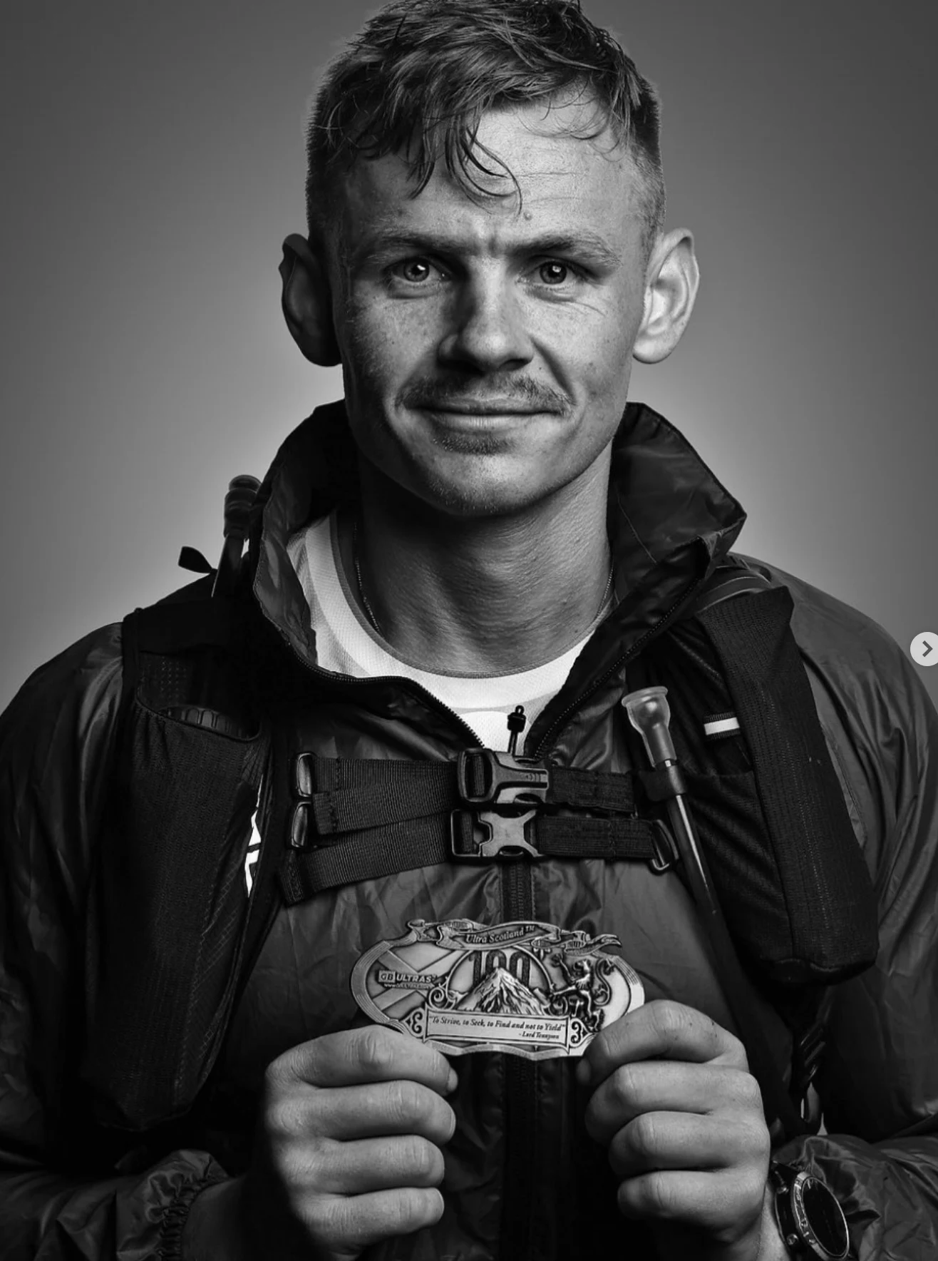 Black-and-white portrait of Jimmy in running kit holding a medal